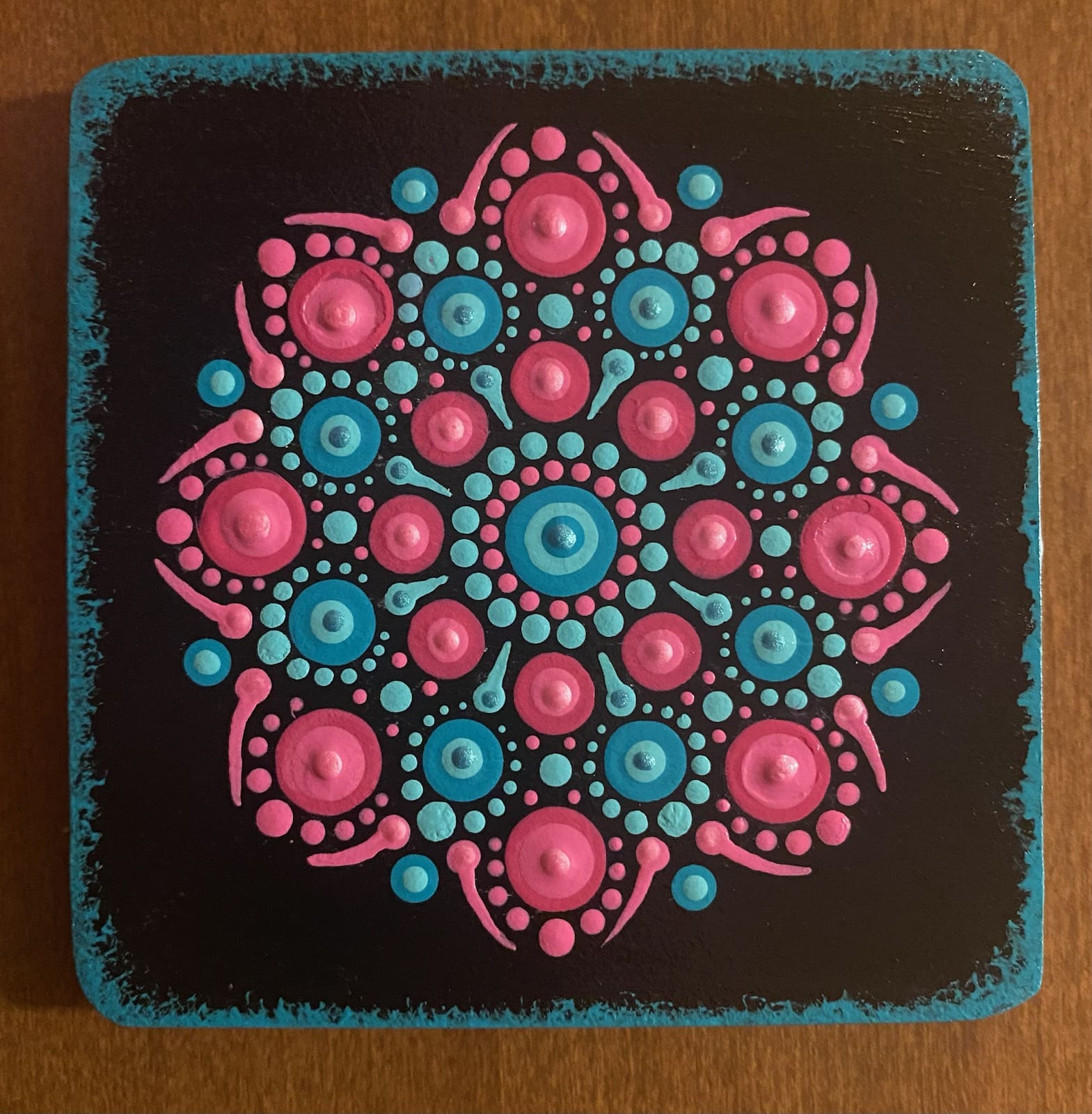 Pink and blue dot mandala on black background.