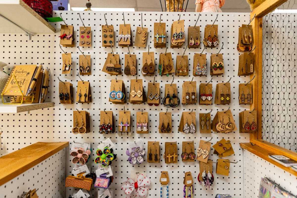 A wall of wooden earrings hanging on the side of a store.