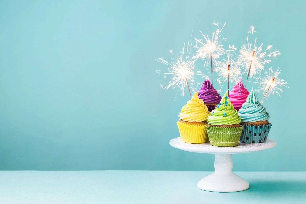 Colorful cupcakes with sparklers on cake stand.